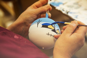 A painter who carefully adds detail to a glass ornament ball in Germany.